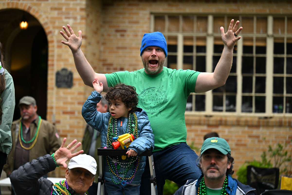 An excited father celebrating the Wearin' of the Green parade with his young son. Waiting to catch beads on a stepladder.