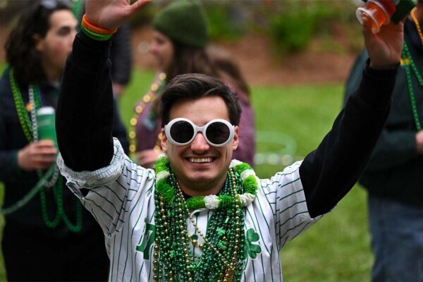 A man in white "willy wonka" style sunglasses waves to the camera during the 2023 parade