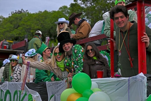 Riders wearing silly hats enjoy the 2023 parade form their float
