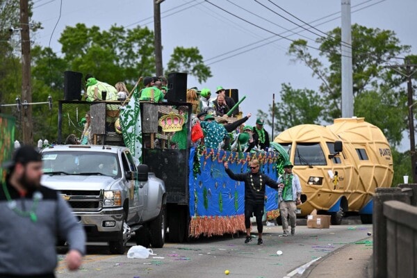 The Planters Nutmobile and a float cross the Perkins Rd overpass during the 2023 parade