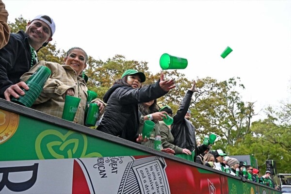 Parade riders throw cups to the crowd in 2023