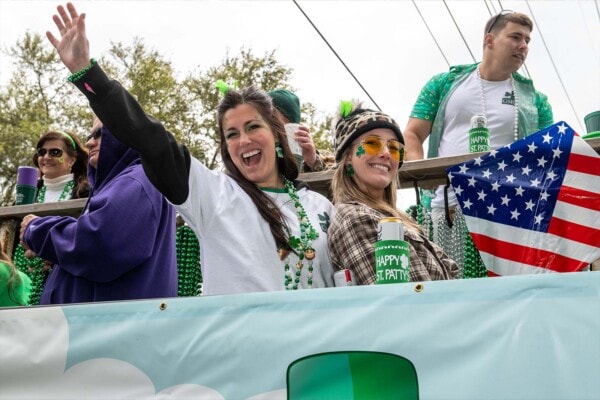 Riders smile and wave to the camera from a float during the 2023 parade