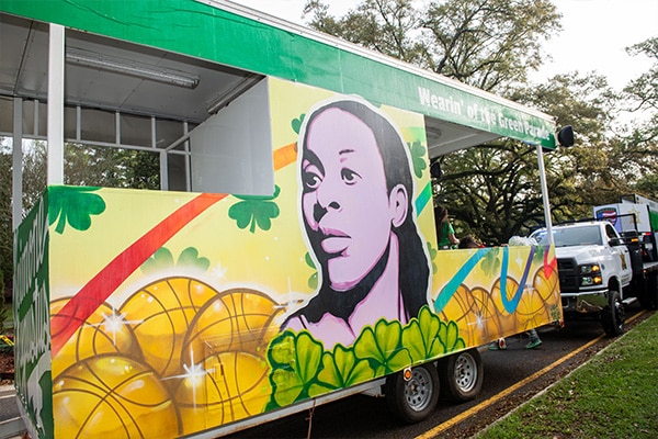 Colorful parade float with a vibrant mural painted by Marc Fresh Art showcasing Seimone Augustus portrait amid artistic elements, ready for the 2024 Wearin' of the Green festive celebration.