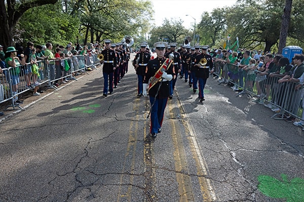 A marching band performing in the 2024 St. Patrick's Day parade with onlookers lining the route, bringing festive music to the celebratory event adorned in green.